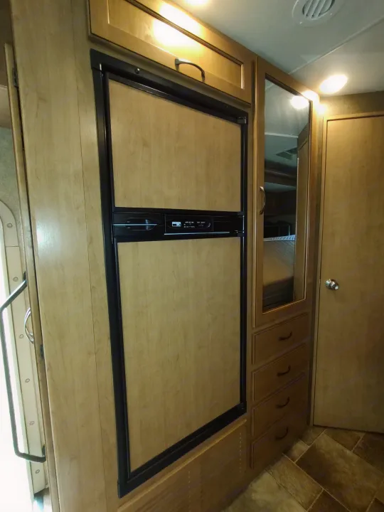 Inside a spacious rv rental, featuring a built-in refrigerator, mirrored cabinet, and overhead storage.. Thor Freedom Elite 2017