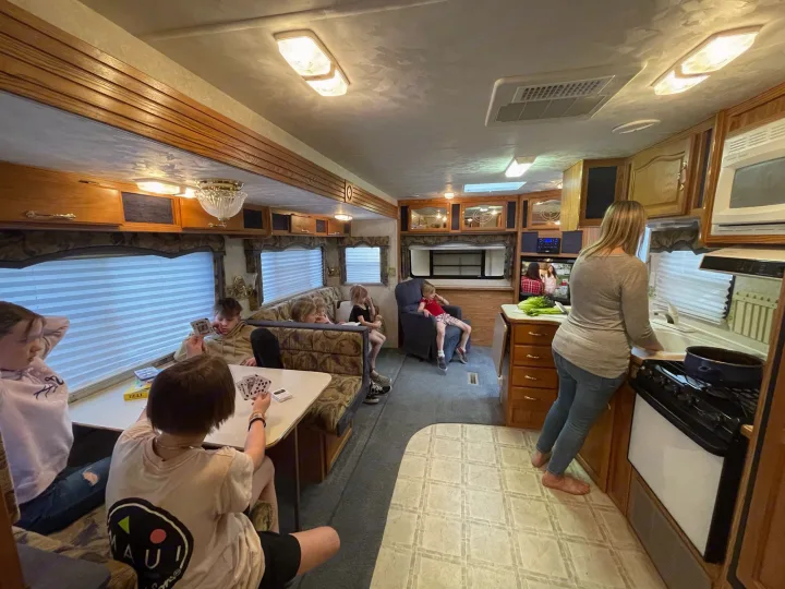 Enjoying an RV rental: a family plays cards and relaxes while a woman cooks in the cozy, well-lit interior.. Komfort Komfort 2003