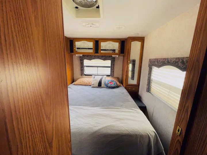 Comfortable RV rental bedroom with a cozy bed, overhead storage, and natural light from the window.. Komfort Komfort 2003