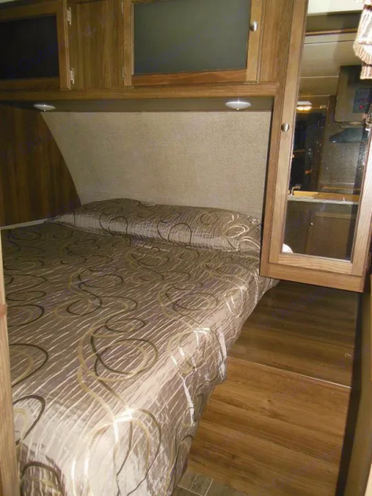 Comfortable RV rental bedroom: full bed, overhead storage, and warm lighting.. Keystone RV Bullet Ultra Lite 2017