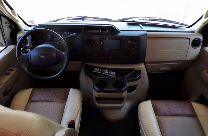 RV rental: Driver's perspective of a spacious cabin interior, featuring the dashboard, steering wheel, and front seats.. Coachmen Leprechaun 2018