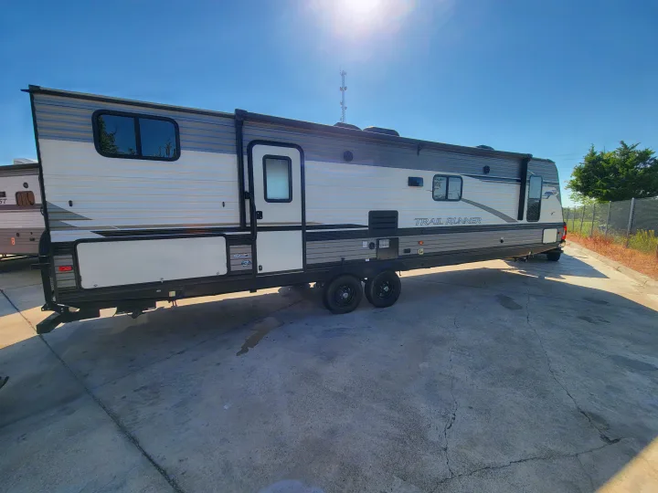 Experience our "Trail Runner" RV rental! This spacious white & gray travel trailer is parked on a sunny lot.. Heartland Trail Runner 2020
