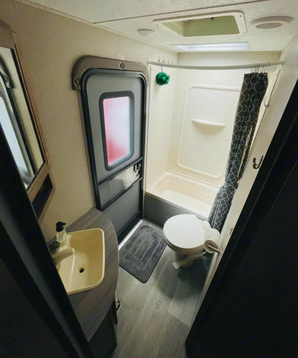 Functional RV rental bathroom: sink, mirror, toilet, & shower/tub combo with curtain. Compact & complete.. Dutchmen Coleman Light LX 2018