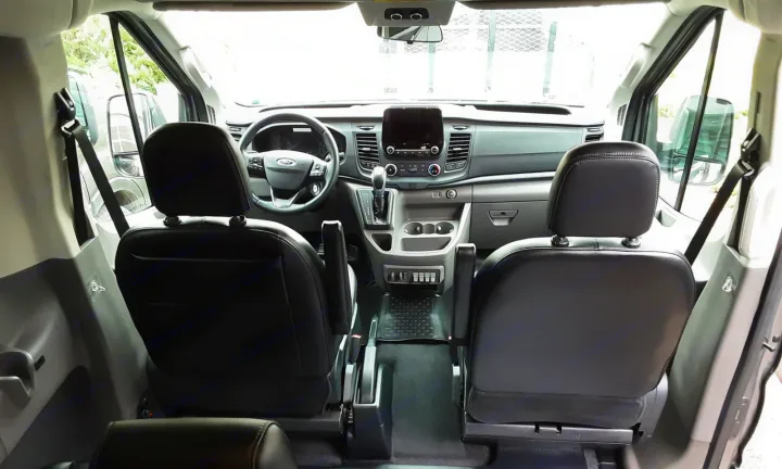 Spacious front cabin of an rv rental van. View of dashboard, steering wheel & seats from the rear.. Ford transit 2017
