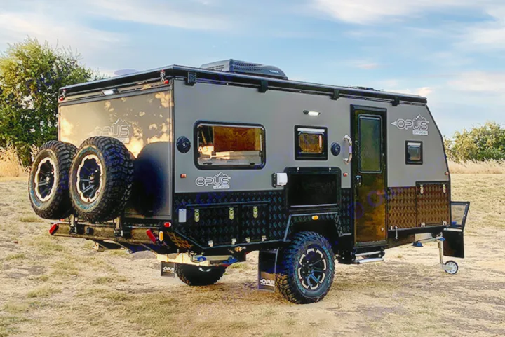 Rugged off-road travel trailer, ideal for rv rental adventures. Grey & black caravan with spare tires on grass, ready for camping.. Other Other 2022