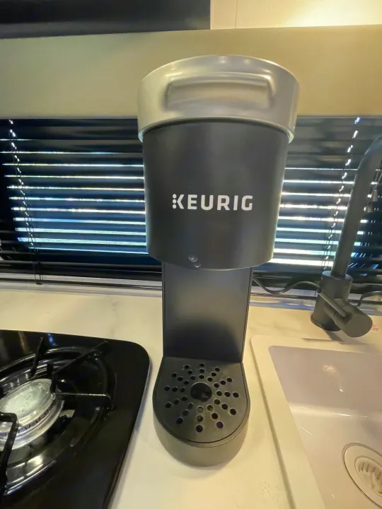 Compact RV rental kitchen with a Keurig coffee maker, stovetop, and sink, offering convenient amenities.. Keystone Springdale 2022
