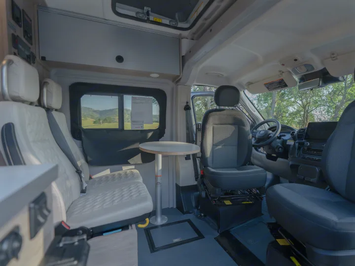 Interior of an rv rental, showcasing versatile seating, removable table, and the driver's cockpit.. Winnebago Solis 59PX 2023