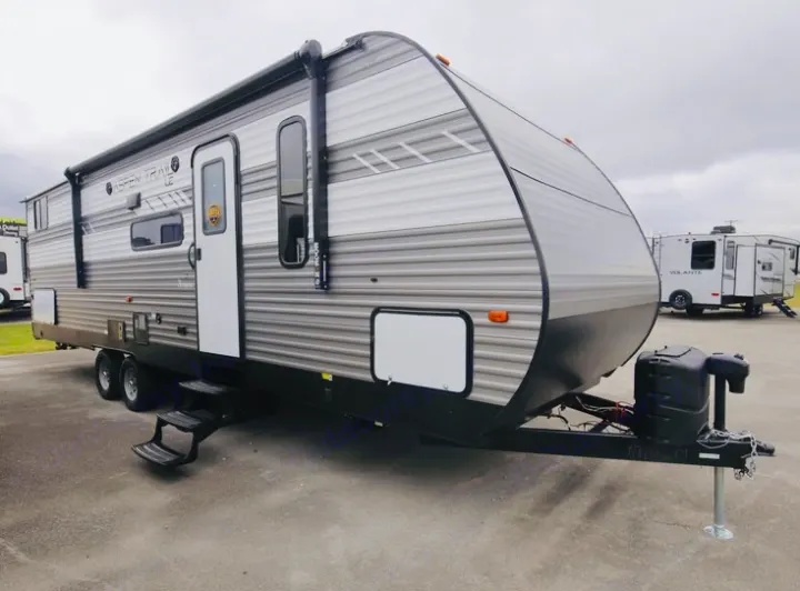 This travel trailer is ready for an RV rental adventure. A new gray and white recreational vehicle with an awning and steps.. Dutchmen Aspen Trail LE 2023