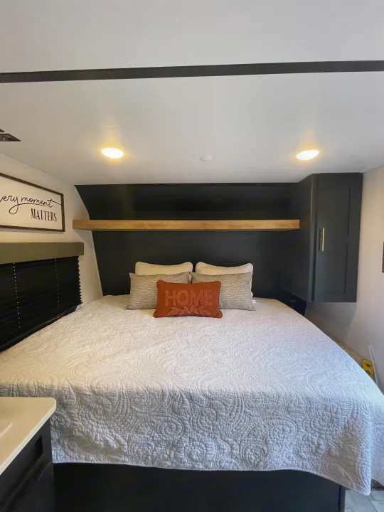 Step inside this cozy RV rental's bedroom, complete with a comfy bed, wall art, and practical storage.. Keystone Springdale 2022