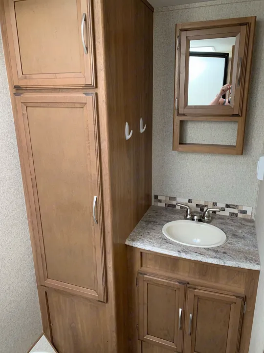 RV rental bathroom: wood cabinets, sink, and mirrored medicine cabinet. Compact yet functional space.. Coachmen Apex 2016