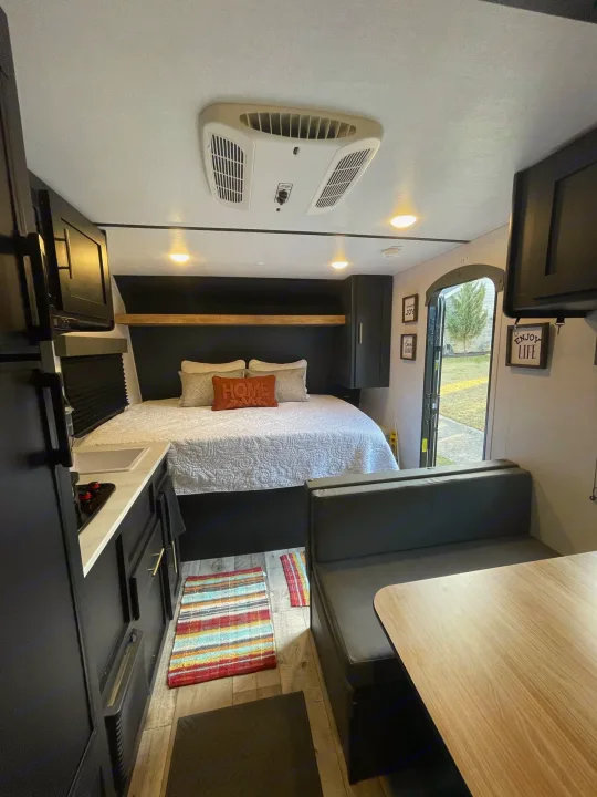 Cozy modern RV rental interior with bed, kitchen, and dining booth. Perfect for travel adventures!. Keystone Springdale 2022