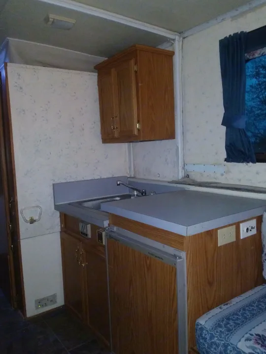 Inside an RV rental: a compact interior with wood cabinetry, fold-down sink, and sleeping/seating area.. K-Z Manufacturing Coyote 2002