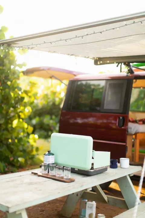 RV rental camping setup: portable stove, picnic table, and cozy van awning with string lights.. Volkswagen Eurovan 2003