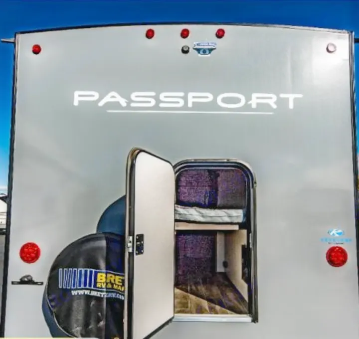 Rear of a grey Passport travel trailer RV rental with an open bunk area, showcasing its interior. Ready for camping and adventure.. Keystone RV Passport SL 2021