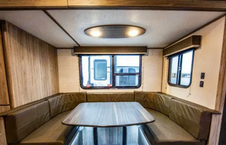 This RV rental's inviting interior features U-shaped dinette seating, a table, and windows.. Keystone RV Passport SL 2021