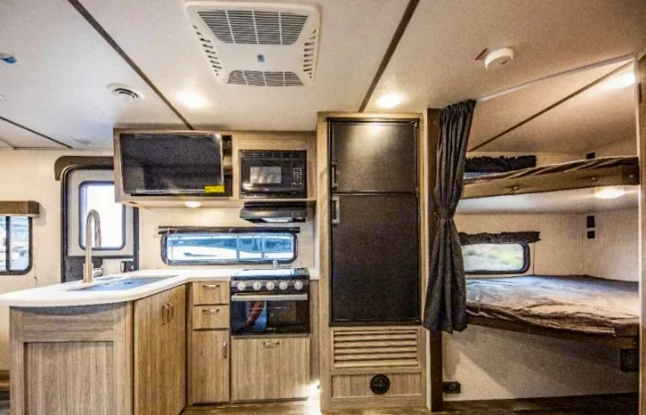 Inside this RV rental: a compact kitchen, comfortable bunk beds, and integrated living space. Ideal for family trips.. Keystone RV Passport SL 2021