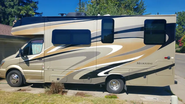 Gold and black Melbourne Class C RV rental with stylish graphics, parked outdoors. Ready for adventure.. Jayco Melbourne 2017