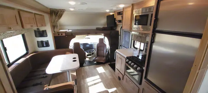 Spacious RV rental interior featuring a modern kitchen, dining booth, and cab-over bunk bed. Ideal for comfortable motorhome travel.. Forest River Sunseeker 2020