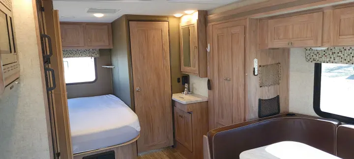 Cozy RV rental interior with bed, dinette, and small sink area, showcasing a compact living space.. Forest River Sunseeker 2020