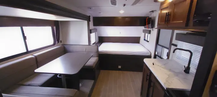 This RV rental interior features a cozy dinette, comfortable bed area, and a compact kitchen counter with a sink, all in one view.. Forest River Wolf Pup 2020