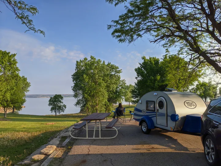 Lakeside campsite featuring a T@G teardrop RV rental, picnic table, and person relaxing by the water.. T@G T@G Trailer 2016