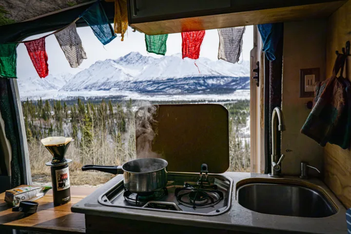 RV rental kitchen with boiling water & coffee brewing, framed by prayer flags and majestic snowy mountains.. Ford Transit Custom 2015