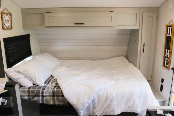 Relax in this clean and cozy RV rental bedroom. Features a comfortable bed with white bedding, storage, and decor.. Forest River Salem FSX 2021