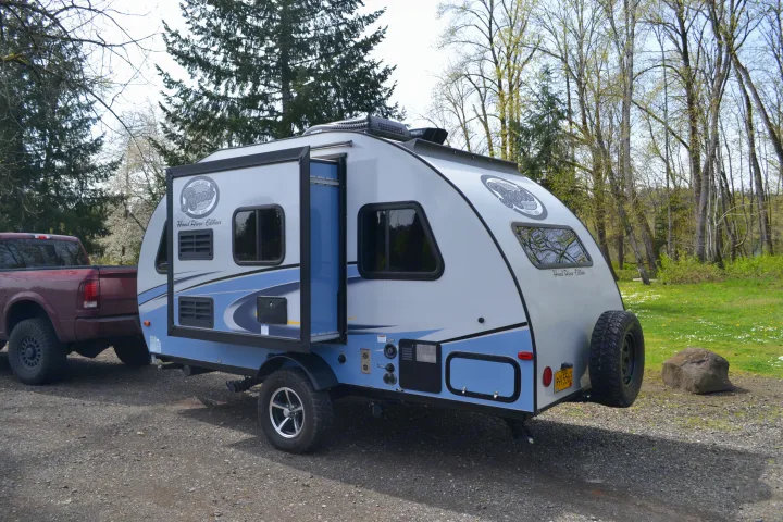 RV rental: A light grey and blue Rpod travel trailer attached to a maroon pickup truck on gravel, surrounded by trees.. R-Pod R177 2018