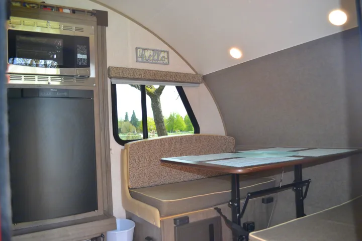 Explore this modern rv rental interior: a compact kitchen with appliances, comfortable dinette, and scenic window view.. R-Pod R177 2018