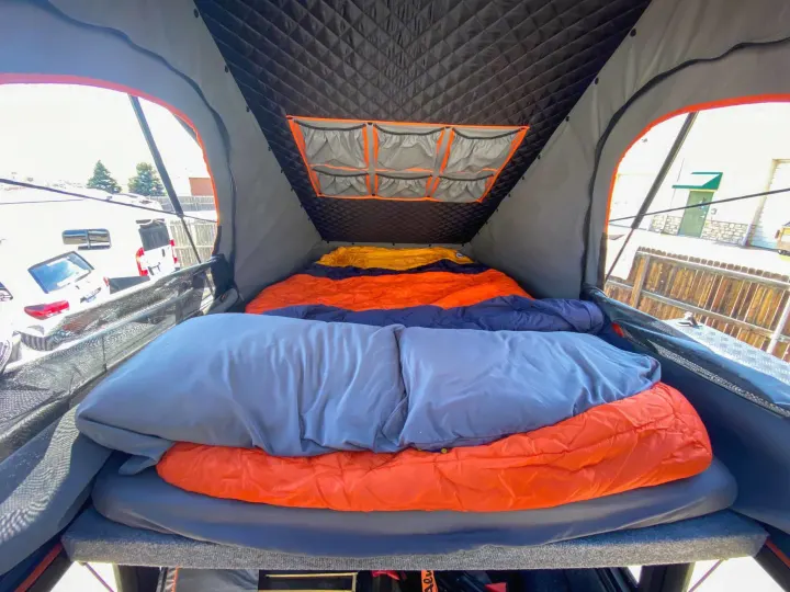 Inside a spacious rooftop tent with comfortable bedding and handy storage pockets, perfect for RV rental trips.. Toyota Tundra 2021