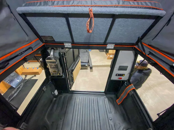 Inside a truck bed camper: A cozy sleeping platform, integrated power panel, and heating system for RV rental adventures.. Toyota Tundra 2021