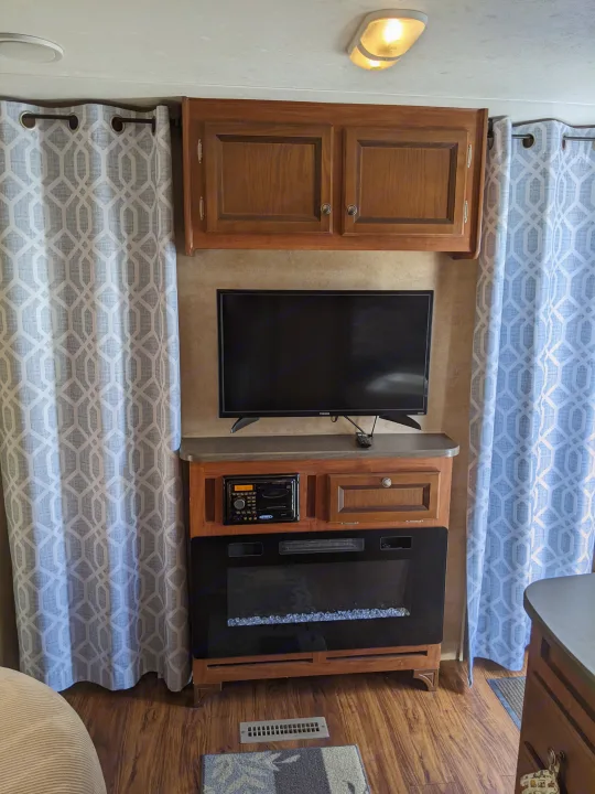 Cozy RV rental interior featuring an entertainment center with a TV, electric fireplace, and stylish geometric curtains.. Jayco Jay Flight 2012