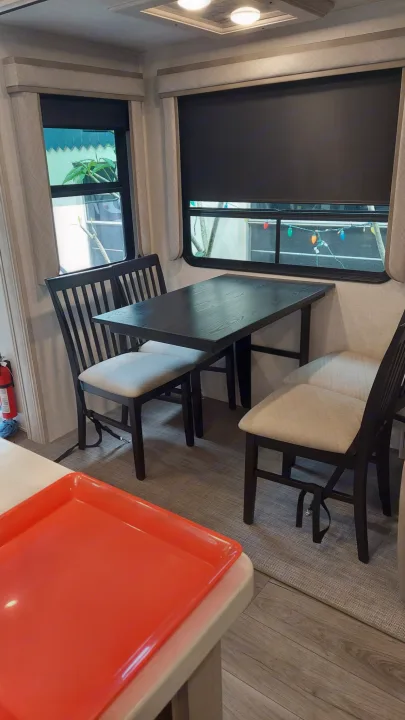 RV rental interior featuring a dining table with chairs, large windows, and an orange tray on the counter, offering a cozy space.. East to West Tandara 2021