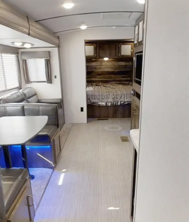 Modern RV rental interior with living, dining, kitchen, and bedroom areas. Bright and spacious layout.. Keystone Passport 2020