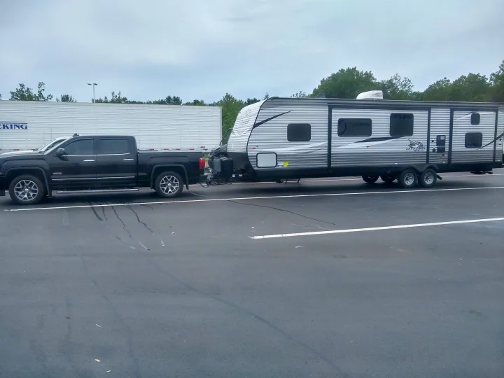Black pickup truck towing an RV rental travel trailer, parked for a recreational road trip. Perfect for camping adventures.. Jayco Jay Flight SLX 2021