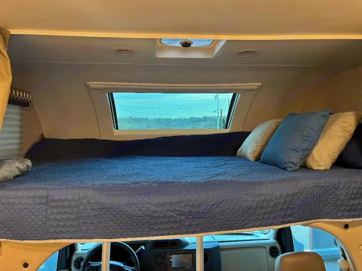 Comfortable RV rental cab-over bunk bed. This spacious sleeping area features a blue quilted mattress and pillows.. Thor Quantum 2022