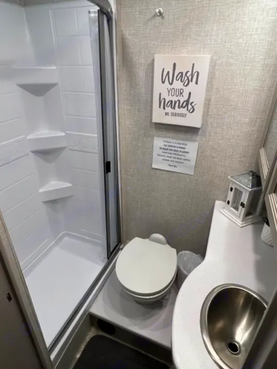 RV rental bathroom with toilet, sink, and shower. Signs remind users to wash hands and clarify flushing rules.. Thor Quantum 2022