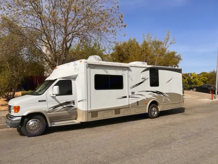 White & tan Class C RV rental parked outdoors. This spacious motorhome is ready for your next adventure.. Itasca Cambria 2008
