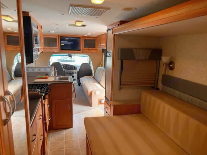 View inside a well-lit rv rental, highlighting the kitchen, flexible living/sleeping area, and driver's cabin.. Itasca Cambria 2008