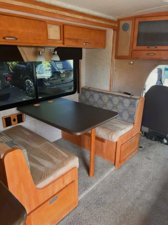 RV rental interior: cozy dinette and functional kitchen with warm wood finishes and carpeted floor, offering comfort.. Itasca Cambria 2008
