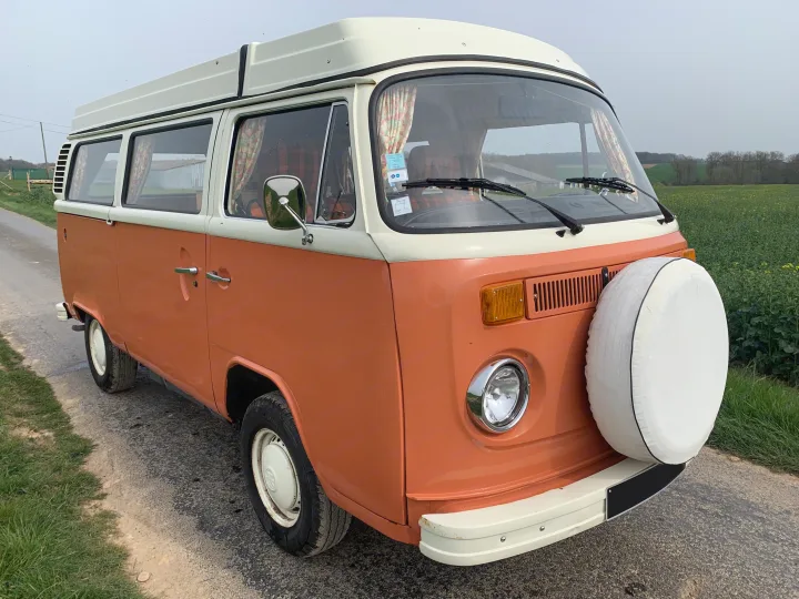 Vintage orange & white VW camper van with pop-top roof, parked on a country road. Perfect for RV rental escapades.. Volkswagen westfalia 1974