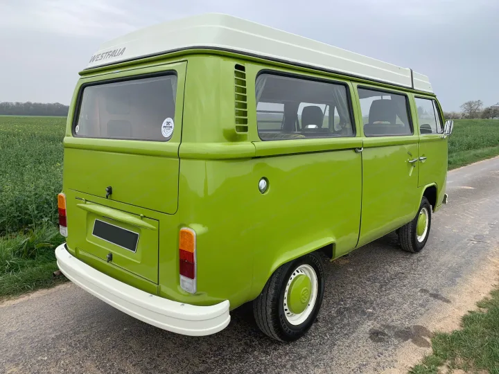 A vibrant green VW Westfalia camper van with a white pop-top roof, parked on a rural road. Ideal for an RV rental adventure.. Volkswagen westfalia 1978