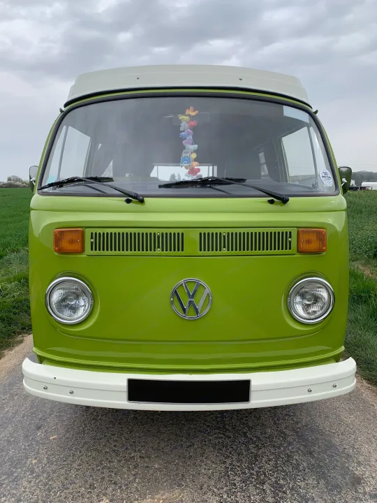Vibrant green VW camper van, ideal for a scenic RV rental journey, parked by a field under cloudy skies.. Volkswagen westfalia 1978