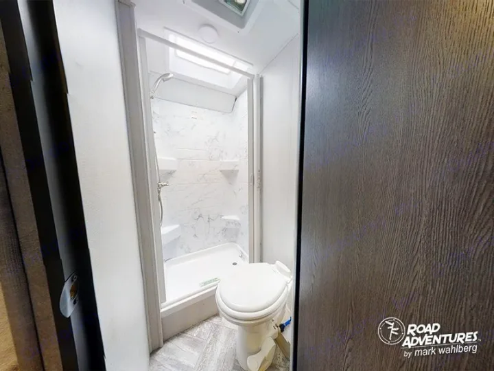 RV rental interior: A bright, modern bathroom featuring a walk-in shower with marble-look walls and a toilet.. Forest River Sunseeker 2023