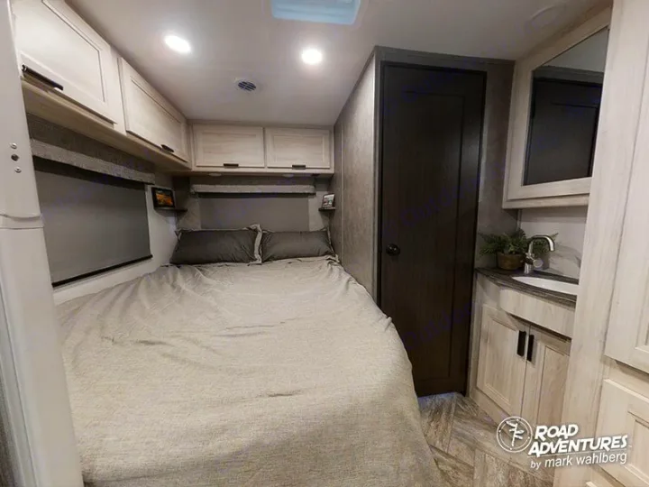 Spacious RV rental bedroom, featuring a comfortable bed, overhead storage, and a sink vanity.. Forest River Sunseeker 2023