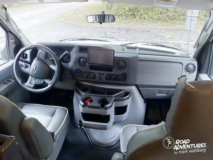 RV rental cockpit: Spacious interior with steering wheel, dashboard, and front seats for comfortable travel.. Forest River Sunseeker 2023