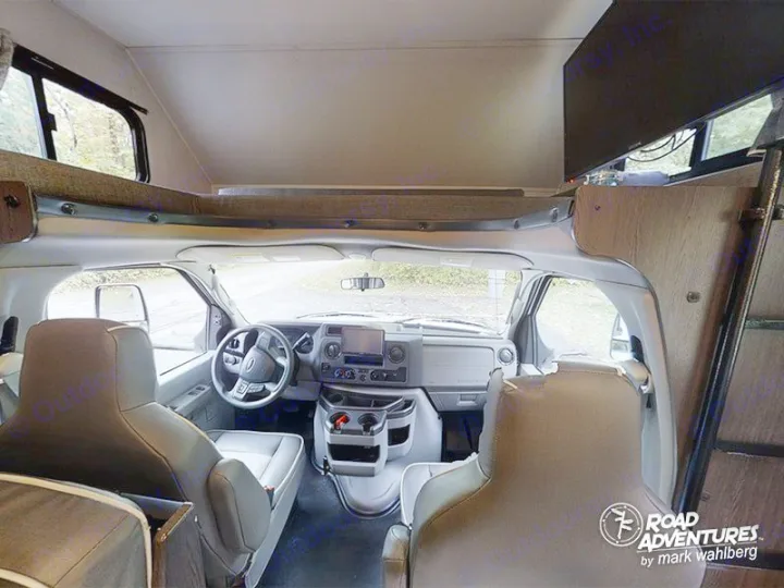 This RV rental interior shows the front cockpit, plush seats, and overhead bunk bed area. Ready for your adventure.. Forest River Sunseeker 2023