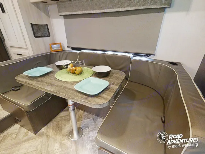 Cozy RV rental interior shows a U-shaped dinette with comfortable cushions and a table, ideal for meals or relaxing during trips.. Forest River Sunseeker 2023