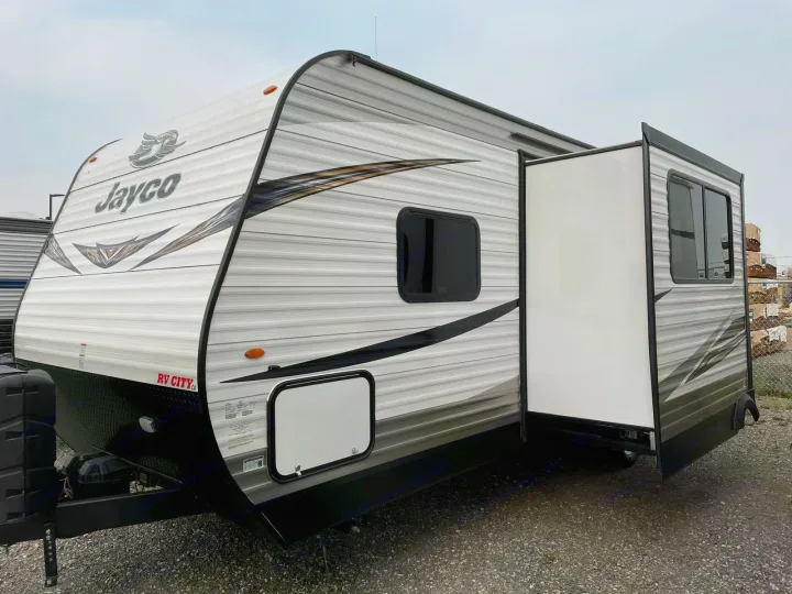 A white and gray Jayco travel trailer with an extended slide-out, ideal for your next RV rental adventure.. Jayco Rocky Mountain 242BHSW 2019