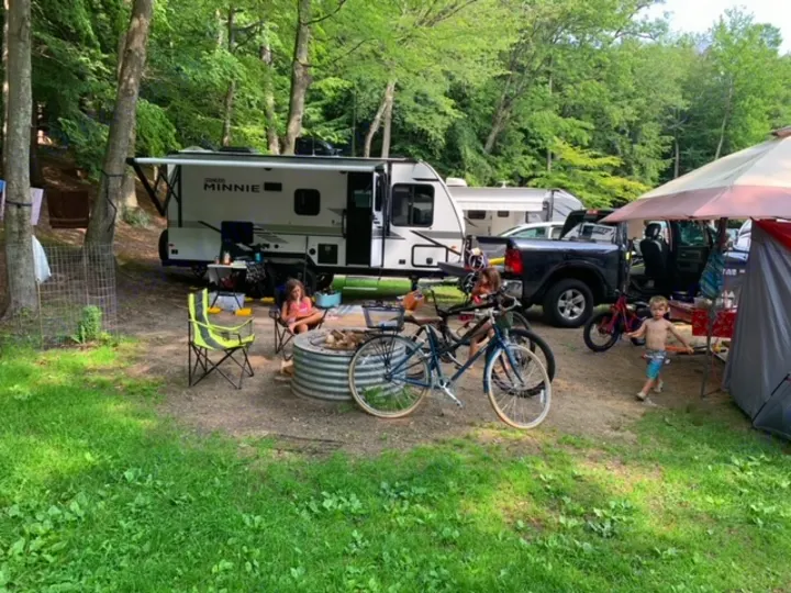 Family enjoying a scenic RV rental campsite with a camper, bikes, and fire pit.. Winnebago Micro Minnie 2021